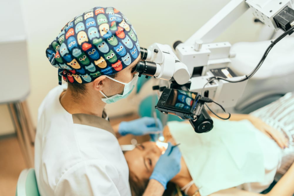 Oral Surgeon examine mouth of female patient with microscope