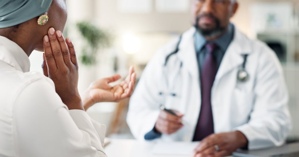 Oral Surgeon with patient grabbing her face and discussing her jaw pain for tmj treatment.