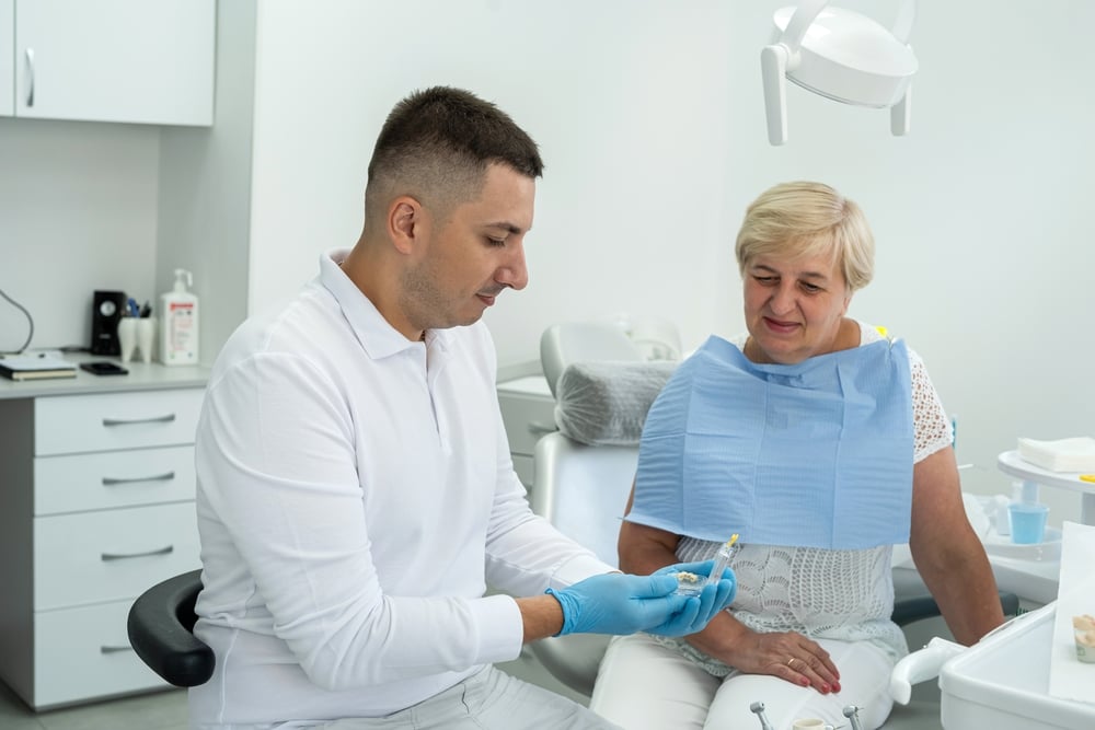 Oral Surgeon sits with patient in chair to explain surgery