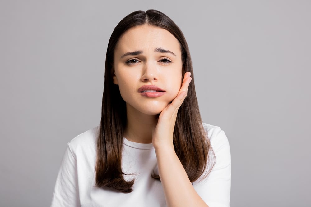 woman suffering from a tooth ache and grabbing her swollen face