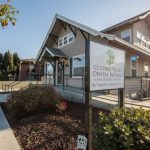 Exterior: “Central Valley Dental Group” sign on post, beige building with gabled roof, shrubs, and clear sky