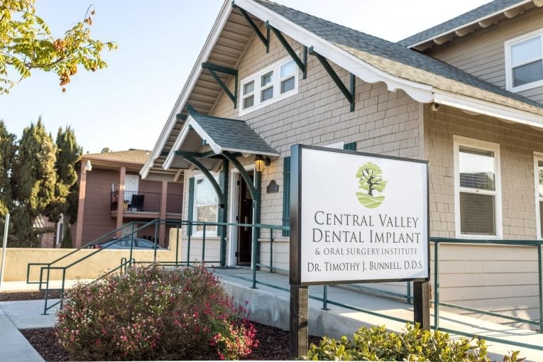 Building entrance: sign reads “Central Valley Dental Implant & Oral Surgery Institute, Dr. Timothy J. Rennell, D.D.S.”; ramp and shrubs visible