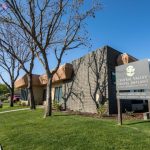 Office exterior: tan building, covered entrance, signpost with practice name and address 1116