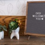 Decorative shelf: two ceramic tooth planters, green succulents, “CVDI WELCOMES YOU” letterboard