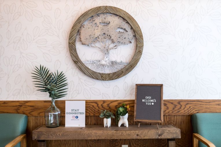 Wall display: circular carved tree art, small potted plant, framed certificate, wood trim