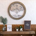 Wall display: circular carved tree art, small potted plant, framed certificate, wood trim