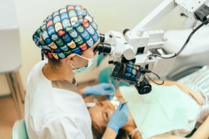 Oral Surgeon examine mouth of female patient with microscope