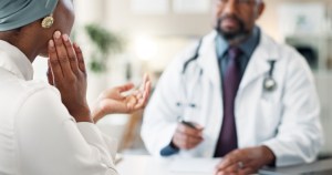 Oral Surgeon with patient grabbing her face and discussing her jaw pain for tmj treatment.